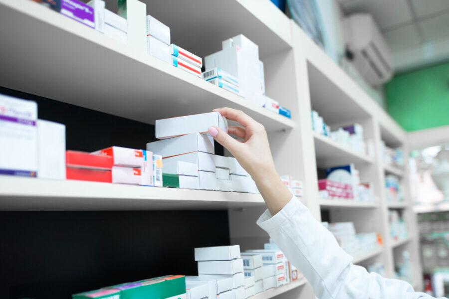 pharmacist hand removing medicine box from shelve